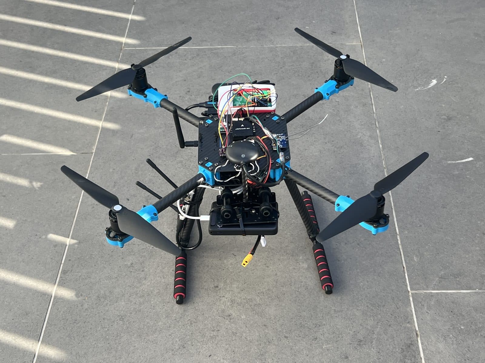 El dron completo visto desde atrás en tres cuartos, con la cámara y el módem 4G en la parte inferior del chasis y las antenas de telemetría desplegadas
