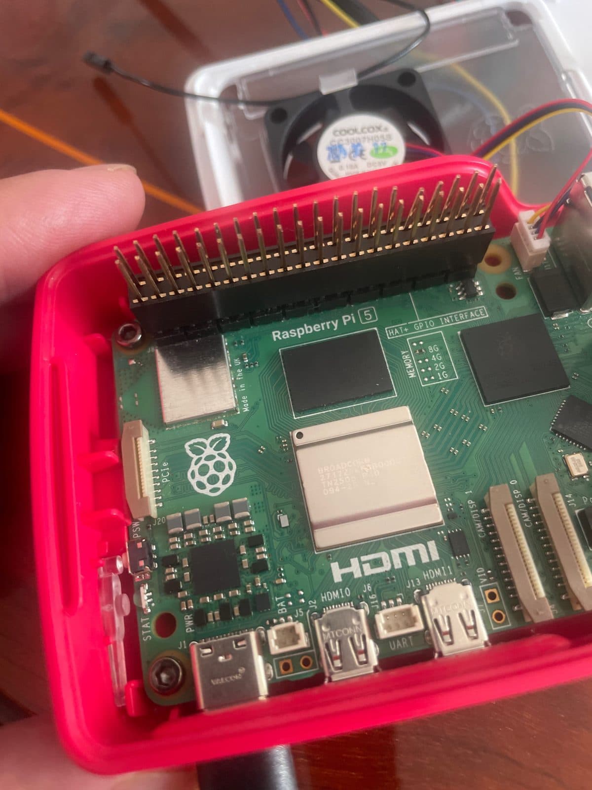 Raspberry Pi 5 en su carcasa oficial, con la regleta extensora de GPIO ya puesta y el ventilador activo al fondo