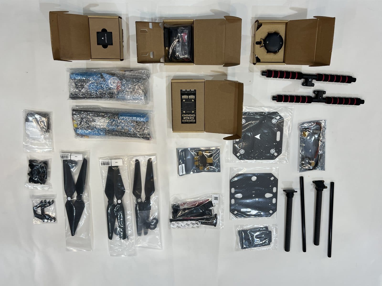 Contenido completo del kit Holybro X500 V2 extendido sobre una mesa: chasis, motores, hélices, controladora y accesorios