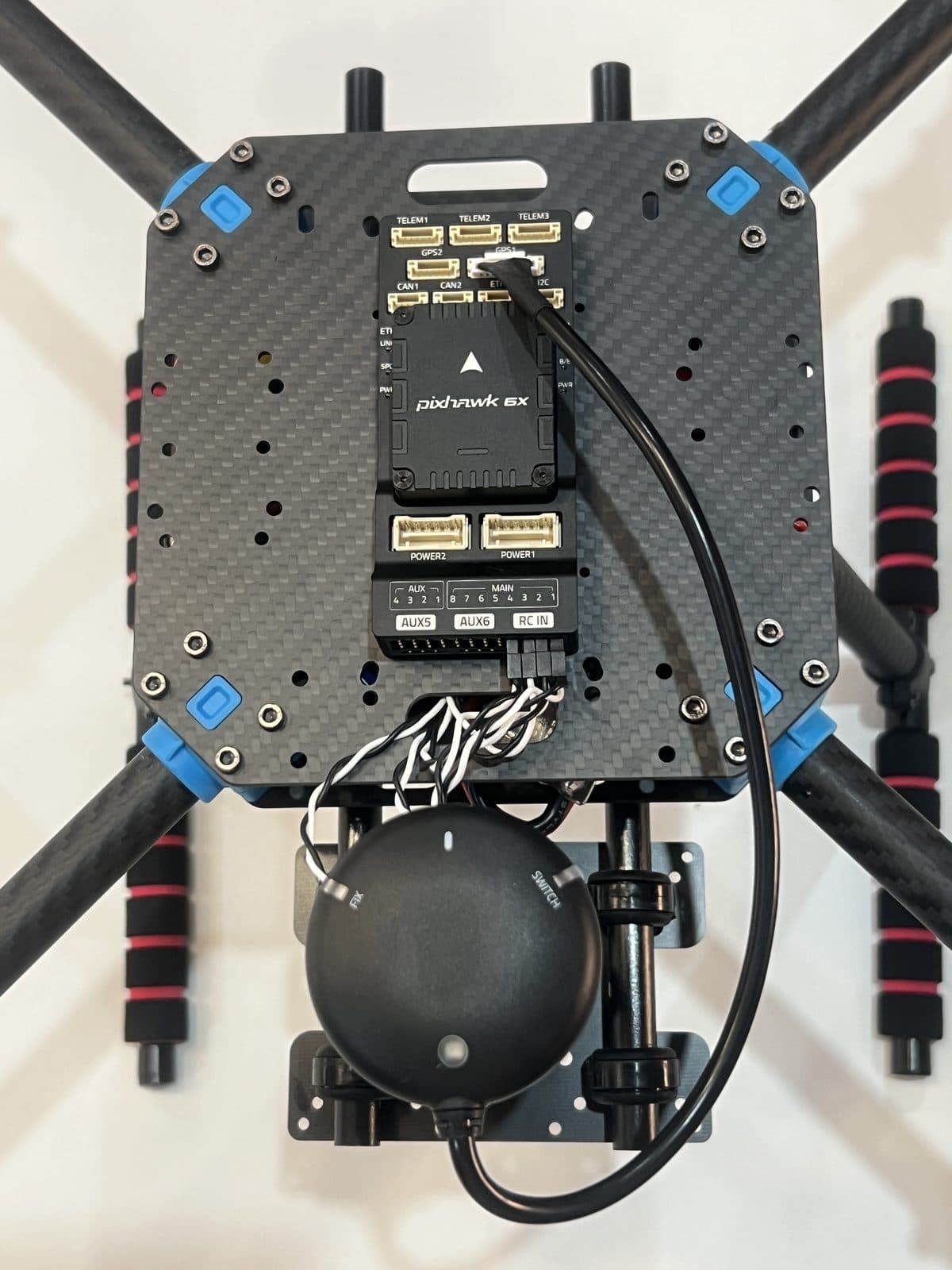 Pixhawk 6X atornillada sobre la placa superior del chasis, con el cableado del GPS y de los ESCs empezando a conectarse